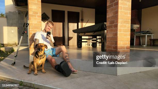 fractured tattooed man photographing his happy dog - indian crutch stock pictures, royalty-free photos & images