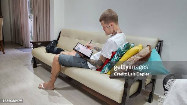 tattooed male wearing orthopedic boots using tablet - indian crutch stock pictures, royalty-free photos & images