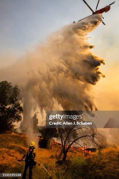 Riverside County, CA A water-dropping helicopter drops water on the Rabbit Fire as CalFire crews defend a Beaumont home from the fire raging in...