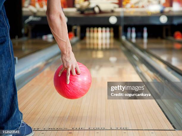 arm holding red bowling ball above skittles alley - man holding bowling ball stock pictures, royalty-free photos & images