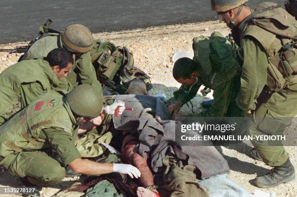 Wounded Israeli soldier is getting first aid by an army doctor and other soldiers at the Israeli-Lebanese border, 08 October, after being wounded in...