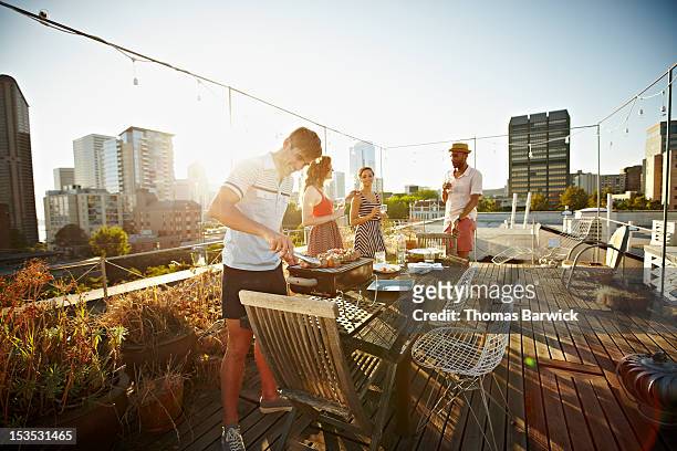 group of friends on rooftop deck cooking dinner - evening meal stock-fotos und bilder