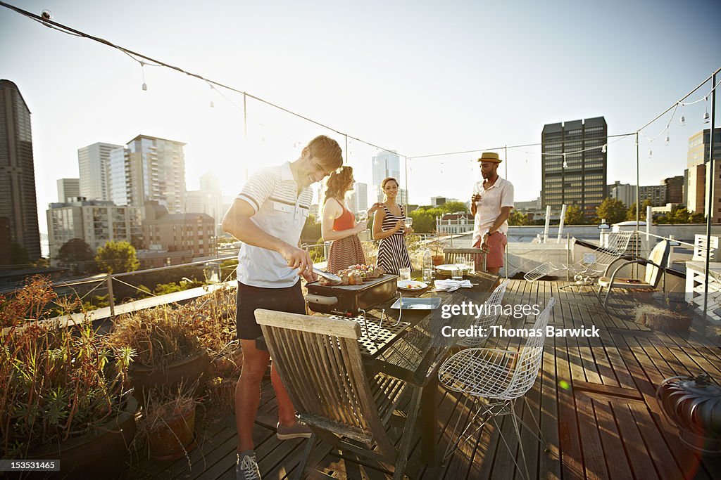 Group of friends on rooftop deck cooking dinner