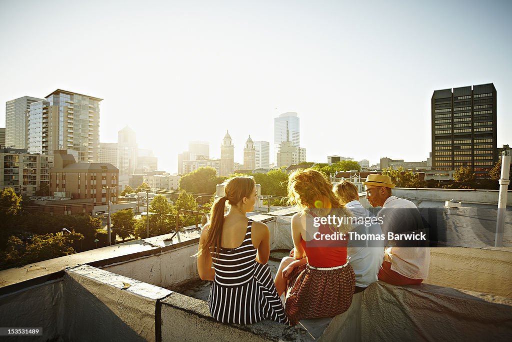 Group of friends sitting on roof at sunset