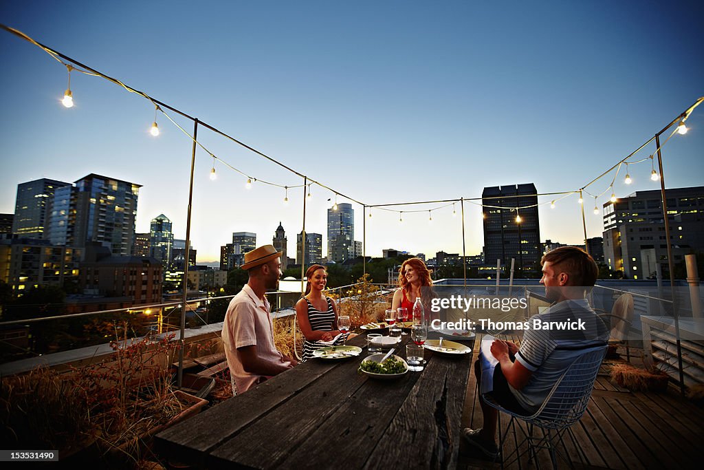 Group of friends dining at table on rooftop deck