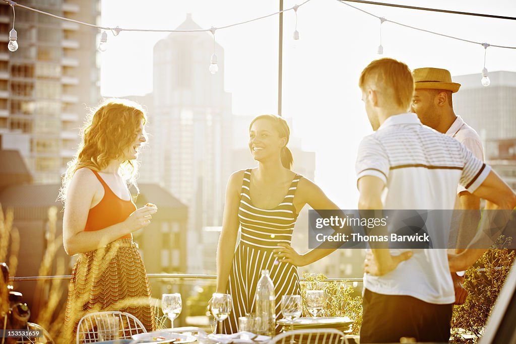 Group of friends standing on rooftop deck laughing