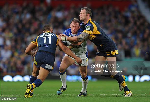 Mick Higham of Warrington Wolves is tackled by Jamie Jones-Buchanan and Jamie Peacock of Leeds Rhinos during the Stobart Super League Grand Final...