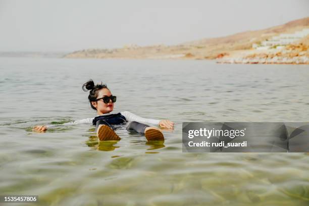 asian woman floating, swimming in dead sea, jordan - balneotherapy stock pictures, royalty-free photos & images
