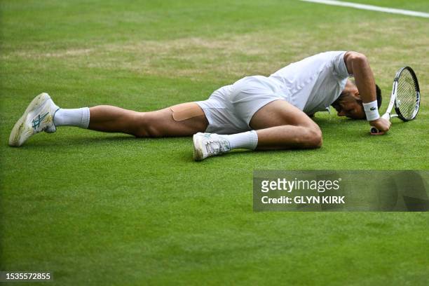 Serbia's Novak Djokovic slips on the grass as he tries to play a return against Spain's Carlos Alcaraz during their men's singles final tennis match...