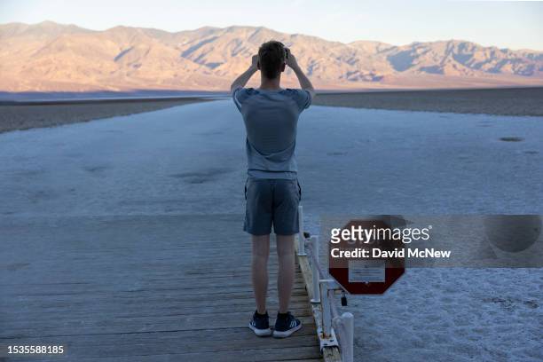 Man takes a photo near a sign warning of extreme heat danger at Badwater, the lowest point in North America at 282 ft below sea level, on a day that...
