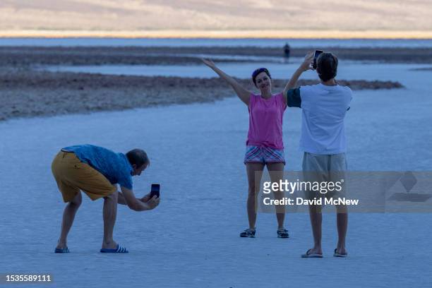 Woman poses on salt flats before the arrival of the early morning sun near a sign warning of extreme heat danger at Badwater, the lowest point in...