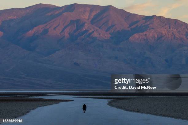 Man walks on the salt flats at dawn at Badwater, the lowest point in North America at 282 ft below sea level, on a day that could set a new world...