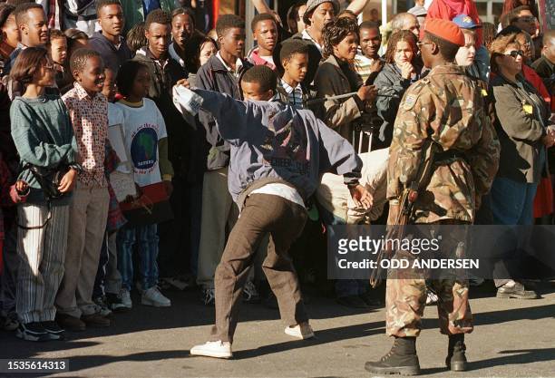 Man performs a "moonwalk" in front of a Namibian soldier , 17 May as an excited crowd waited for the American pop star Michael Jackson to arrive at...