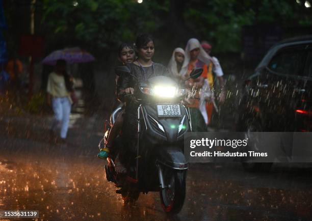 Commuters seen out during light rains at Sector 12 road, on July 15, 2023 in Noida, India.