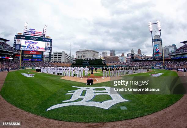The Detroit Tigers and the Oakland Athletics line up on the baselines for the performance of the National Anthem and pregame festivities during Game...