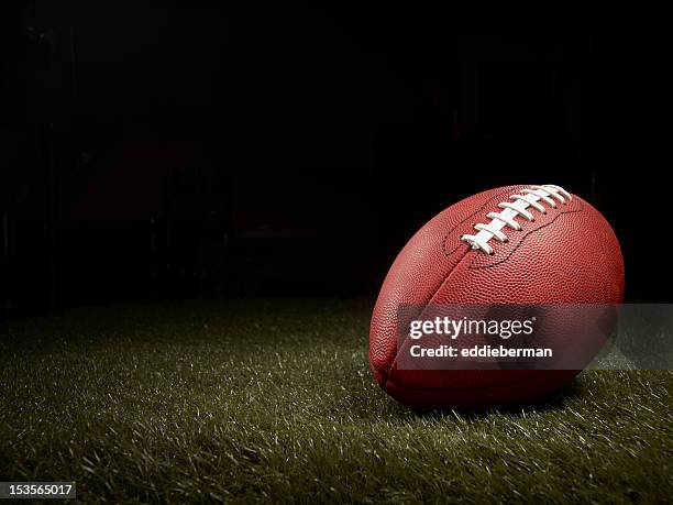 football on a grass field - american football ball stock pictures, royalty-free photos & images