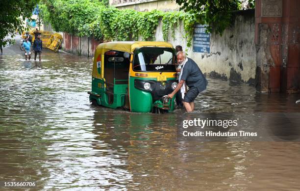 People push an auto from flooded rain water at Kashmere Gate Vihar, on July 16, 2023 in New Delhi, India.