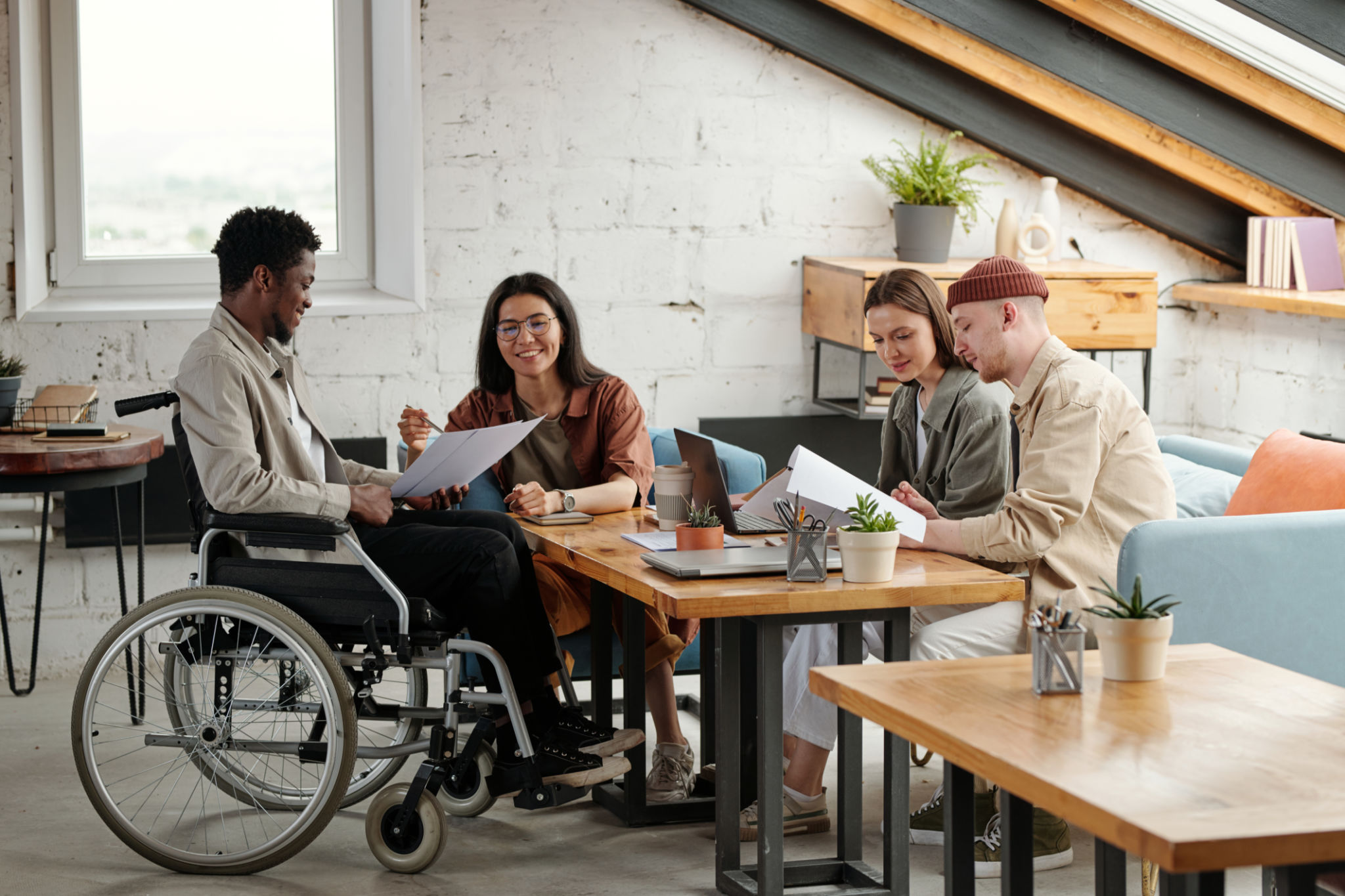 Two pairs of intercultural employees working in small groups by workplace Two pairs of intercultural employees working in small groups by workplace