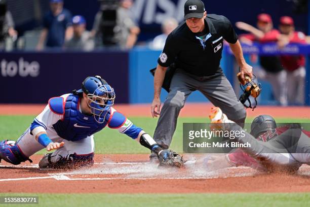 Lourdes Gurriel Jr. #12 of the Arizona Diamondbacks slides into home plate to score ahead of the tag by Danny Jansen of the Toronto Blue Jays during...