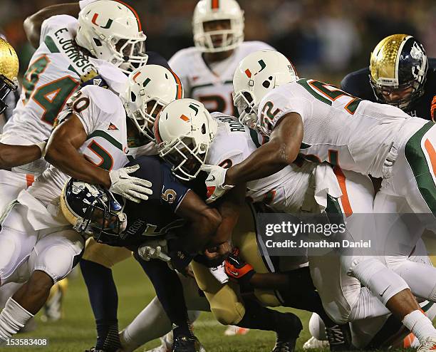 Everett Golson of the Notre Dame Fighting Irish is trackled by A.J. Highsmith, Kacy Rodgers and Denzel Perryman of the Miami Hurricanes at Soldier...