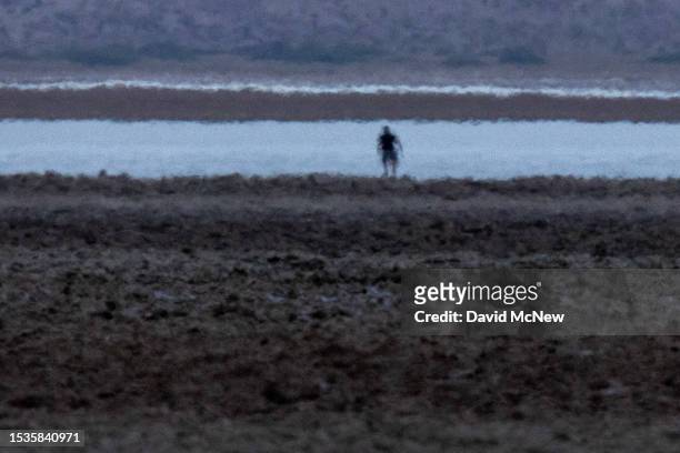 Heat haze distorts the figure of a man hiking before dawn near Badwater, the lowest point in North America at 282 ft below sea level, on a day that...