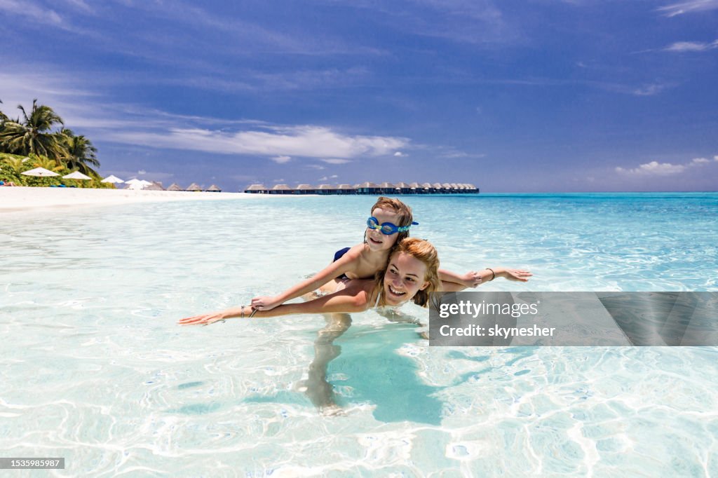 Juguetona madre soltera y su hijo divirtiéndose en el mar.