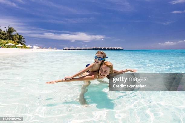 playful single mother and her son having fun in sea. - asian family traveling stock pictures, royalty-free photos & images