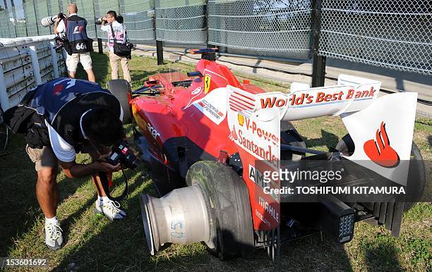 Photographer takes a picture of the retired car of Ferrari driver Fernando Alonso of Spain at the side of the track during the Formula One Japanese...