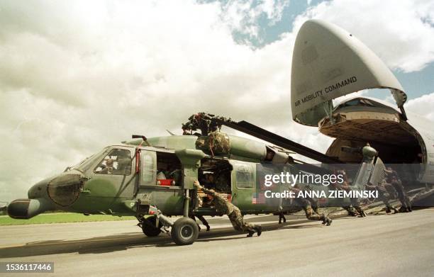 United States airmen push a HH-60 helicopter out of the belly of a C-5 aircraft on its arrival at the air force base in Hoedspruit 07 March 2000. The...
