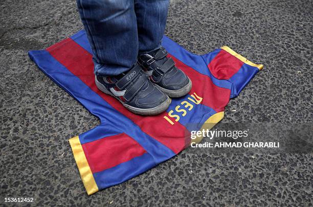 Palestinian boy steps on a T-shirt of Spanish FC Barcelona football club with the name of it's Argentinian player, Lionel Messi, during a...