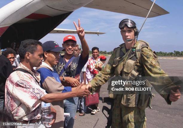 East Timorese refugees , one showing a victory sign, waste no time in shaking hands with an Australian soldier when soldiers disembarked from their...
