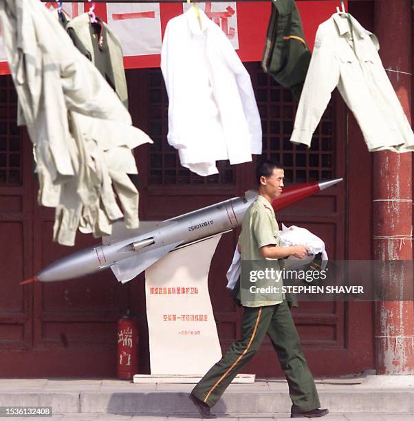 Soldier walks past a missile display and uniforms drying in the sun as he carries his laundry back to his barracks 09 September 1999 in central...