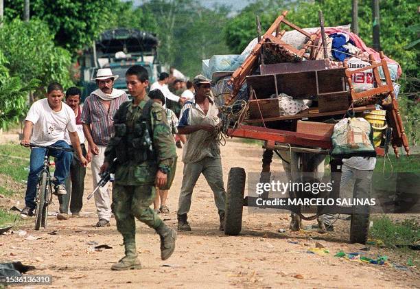 Resident of Puerto Lleras, southeast of Bogota, Colombia, loads his belongings on a horse-drawn cart as he prepares to flee the area, while a...