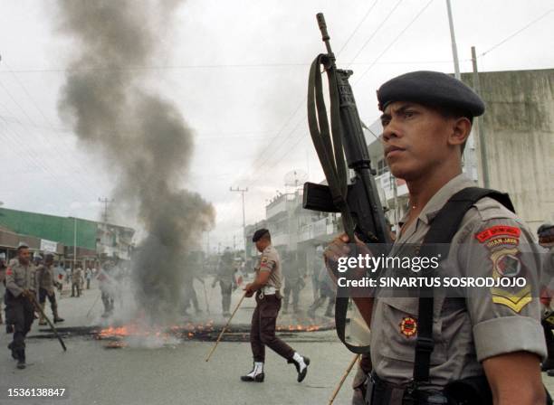 Policeman stands guard on the main road in Sentani, Irian Jaya 09 June 1999 as angry mobs of protesters gathered in the streets after the body of a...