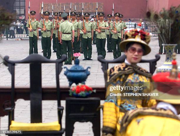 Chinese tourists dressed in Imperial garb pose with traditional Chinese furniture while soldiers practice marching with their bayonettes 04 June 1999...