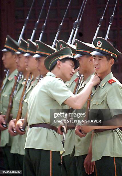 Chinese drill seargant inspects a soldiers neck as they prepare to march with bayonettes at their barracks near Tianamen Square 03 June 1999 in...