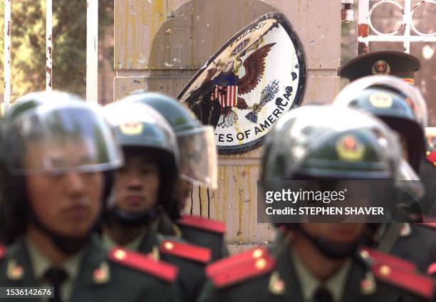 The American seal, splattered with egg yolk, barely hangs on to the US embassy's front gate as Chinese soldiers in riot gear stand guard 10 May 1999...