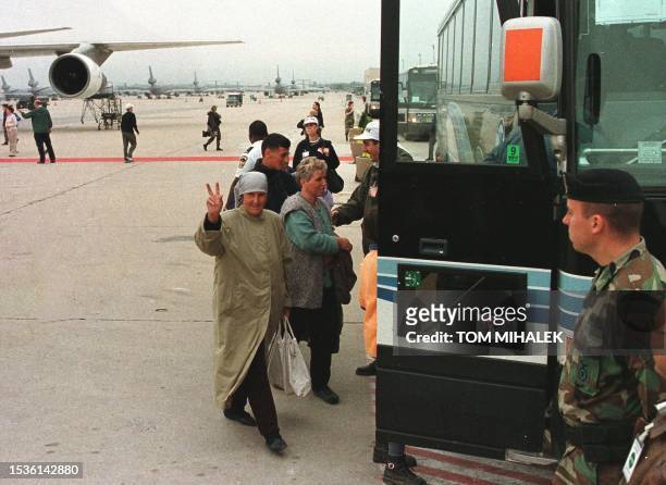 Kosovo refugee makes the peace sign as she and others walks towards a bus on the tarmac of McGuire Air Force base, NJ, after leaving a plane that...