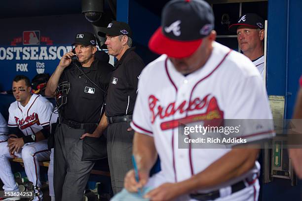 Home plate umpire Jeff Kellog talks on the phone in the Atlanta Braves dugout after a controversial infield fly rule call in the seventh inning of...