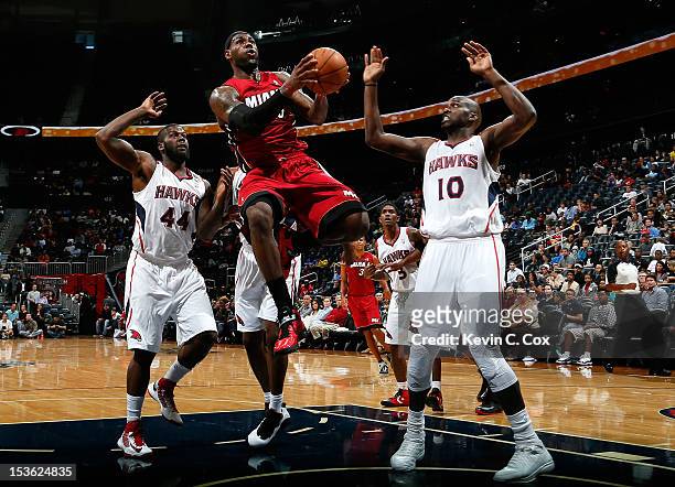 LeBron James of the Miami Heat drives against Ivan Johnson and Johan Petro of the Atlanta Hawks at Philips Arena on October 7, 2012 in Atlanta,...