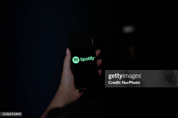 Hand holding a mobile phone with the logo of Spotify on its screen.