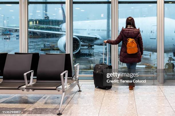 woman looking at a plane at the airport seen from behind - boarding stock pictures, royalty-free photos & images