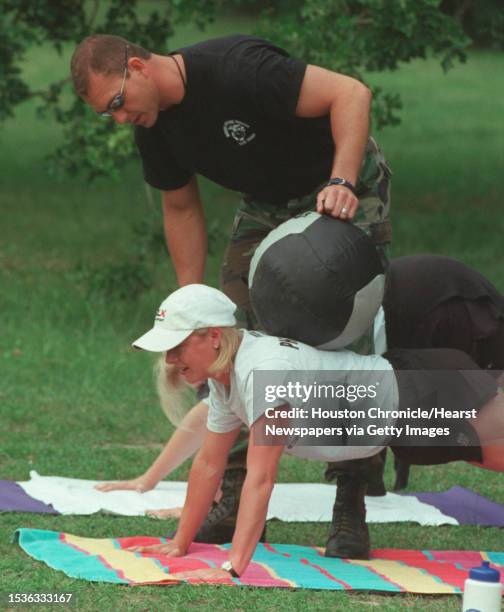 Instructor Craig Luber adds the weight of a medicine ball to the push-ups of Debbie Schnitzer during the 'Marine Physical Training' course that uses...