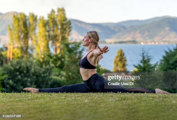 trainieren an einem ruhigen ort in einem park in der nähe eines sees - spagat frau stock-fotos und bilder