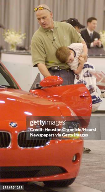 Brian Hilberth holds on to his 3 year old son, Brody Hilberth as he looks at a BMW Z4 Roadster at the Houston Auto Show at Reliant Center. Photo by...