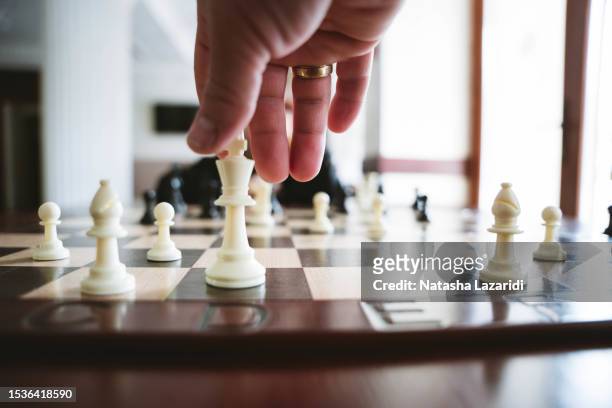 a hand holds a chess piece above the board - chess board overhead stock pictures, royalty-free photos & images