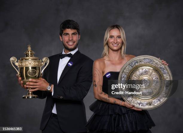 In this handout photo provided by the All England Lawn Tennis Club, Carlos Alcaraz of Spain poses with the Gentlemen's Singles Trophy and Marketa...