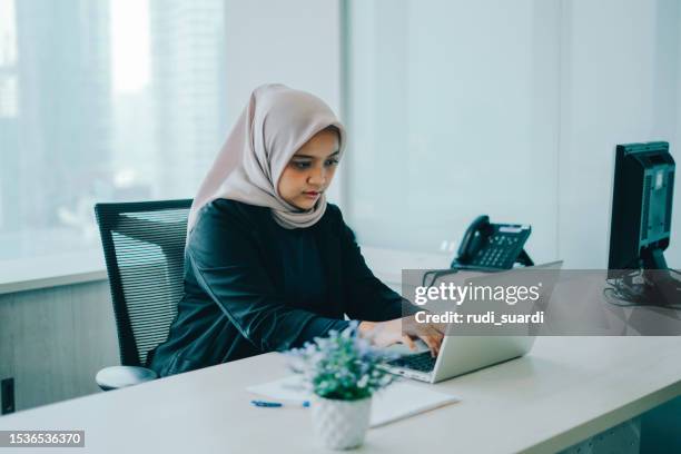 geschäftsmuslimische frau mit computer im büro - kopftuch stock-fotos und bilder