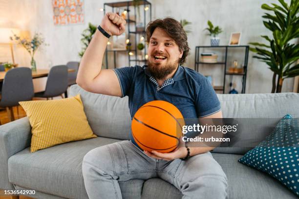 young man watching a basketball game on a tv at home - sportsman channel stock pictures, royalty-free photos & images