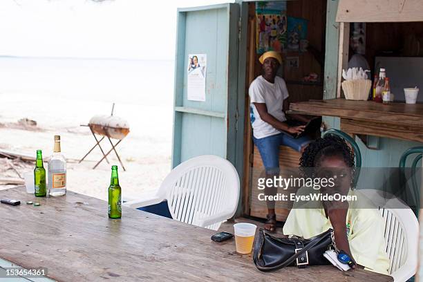 Female local bahamian guest, a young lady, is having a drink at a foodstall at New Bight Beach on June 15, 2012 in Cat Island, The Bahamas.